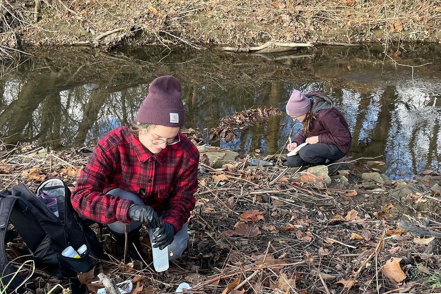 Eliza Siefert (from left), water resources technician at the WVU West Virginia Water Research Institute, and Rachel Spirnak, water resources specialist at WVWRI, collect samples in Chartiers Creek on a sampling day with the Washington County Conservation 